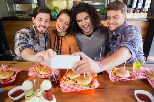 Cheerful friends taking selfie in restaurant