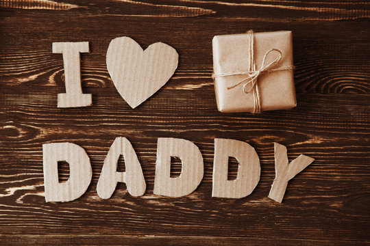 gift box and Fathers Day message from cardboard letters on wooden table. Father's day holiday concept. - Powered by Adobe