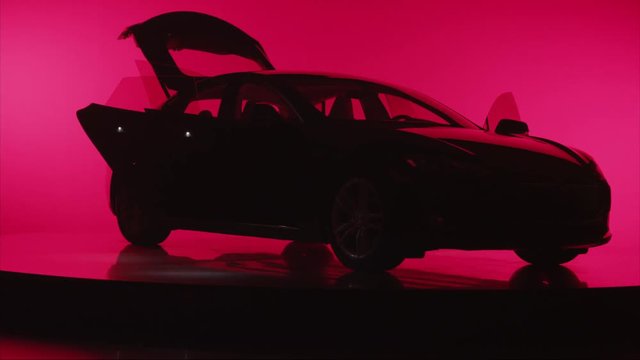 Silhouette of a car against red background, rotating with all doors open