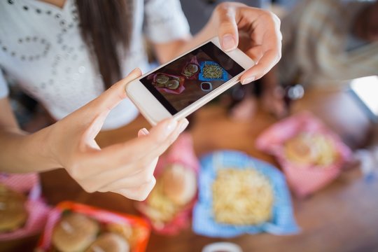 Woman photographing food through mobile in restaurant