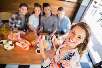 Portrait of woman photographing friends in restaurant