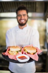 Chef holding burgers in plate at commercial kitchenc