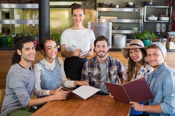 Smiling waitress and customers in restaurant