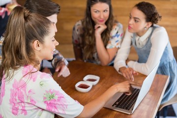 Friends discussing over laptop in restaurant