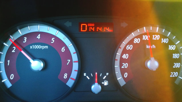 Car dashboard while driving at high speed - a nice number on the odometer, the bright glare of the sun. Blurry