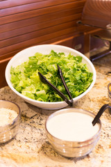 Green salad in the white bowl and sour cream
