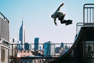 Skateboarder jumping in air, city skyline in background