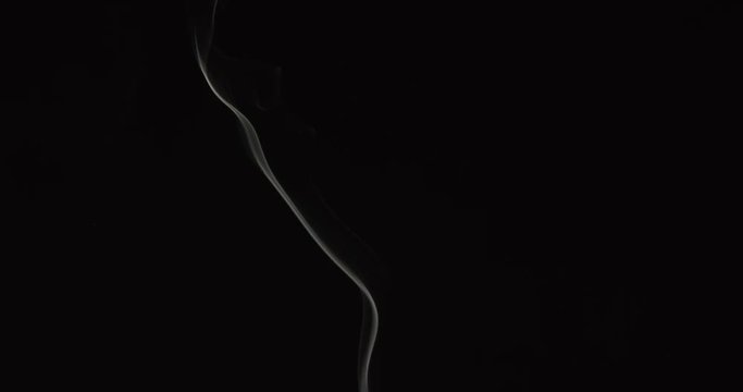 Candle smoke wisps rise in smooth lines against black background