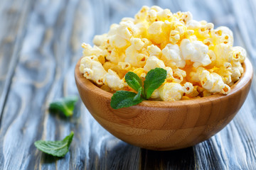 Crispy popcorn with salt in a wooden bowl closeup.
