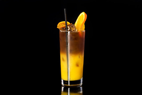 Closeup glass of fresh orange juice mixed with coffee at black isolated background.