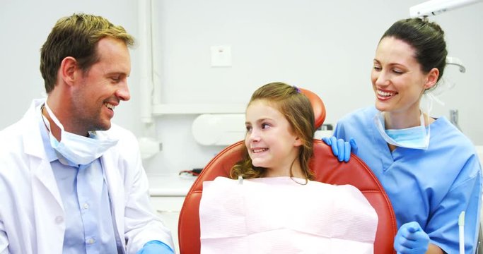 Portrait of smiling dentists and young patient showing thumbs up