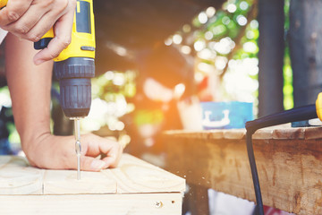 Carpenter's screwing a wood plate by wireless drill for make a chair, Diy at Home concept