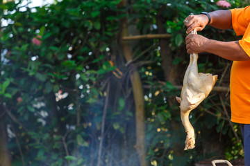 A man burning a chicken for remove a feather before cooking,Local cleaning chicken in Thailand.