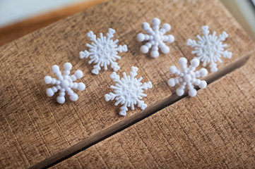 Fototapeta premium Snowflakes on a wooden background. Snow in the macro. Buttons in the form of snowflakes on a wooden board