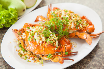 Fried red crab with onion, lettuce and herbs on white dish