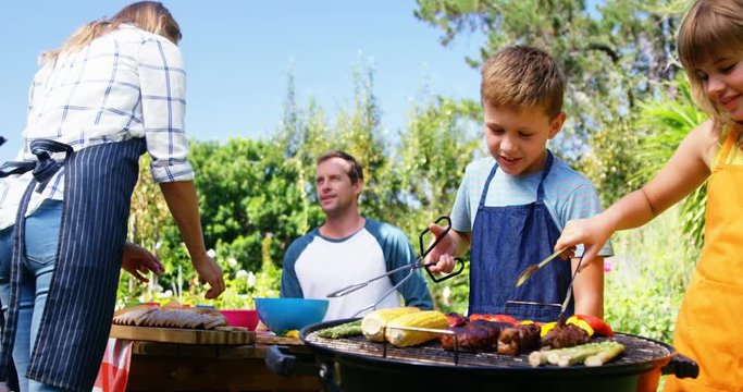 Kids grilling meat and vegetables on barbecue