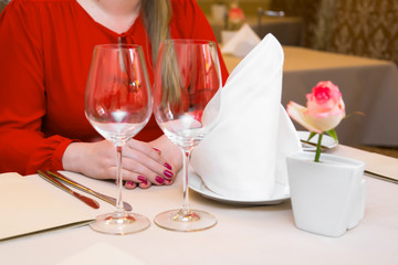 Durk in red is waiting at the restaurant. Table set service with silverware and glass stemware at restaurant before.
