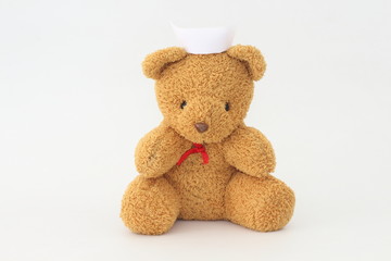 Teddy bear wearing a nurse hat on a white background.