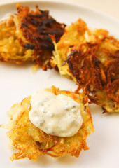 Potato pancakes with creamy sauce on white platter