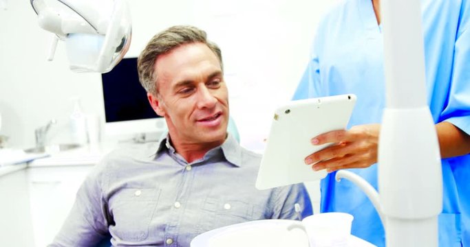 Dentist showing digital tablet to male patient