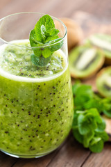 Fresh green kiwi smoothie with mint and honey, healthy organic drink on wooden table