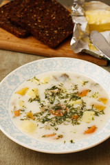 Fish soup with cheese spread on white dish with black bread