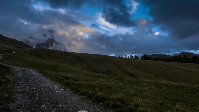 Sunset time-lapse, moving across an open field full with heavy, gray clouds.