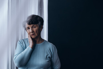 Elderly woman standing beside window