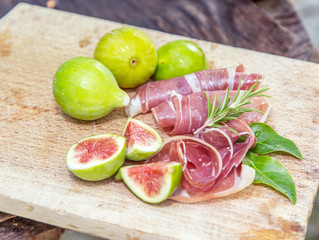 Ripe fig fruits and bacon or prosciutto. Food to accompany the drinks.