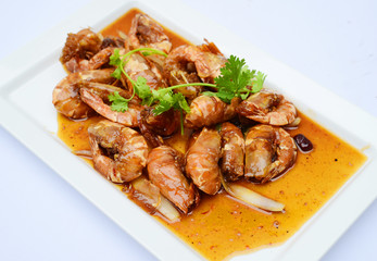 Sauteed shrimp with sauce and herbs on white platter
