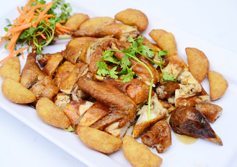 Chopped fried chicken with potatoes and herbs on white platter
