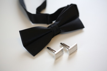 Black bow-tie and silver cuff links on isolated background