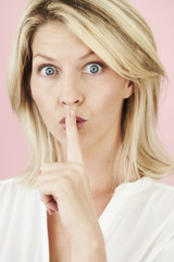 Naklejka premium Blond blue eyed lady with finger on lips, portrait