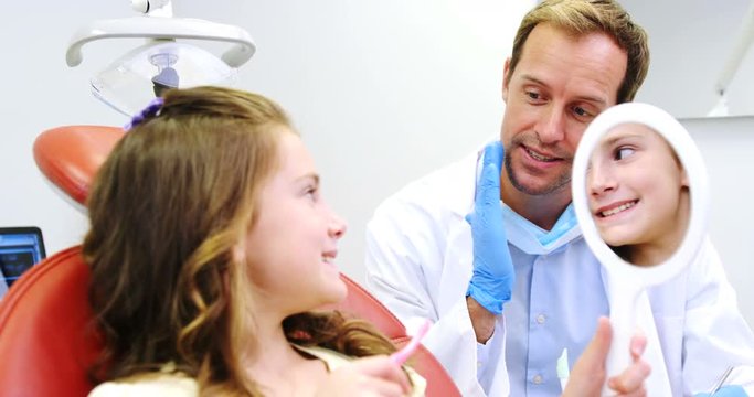 Dentist teaching girl to a brush teeth