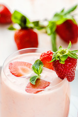 Strawberry yogurt in a glass with slices of fresh berries, mint leaves and ripe strawberries
