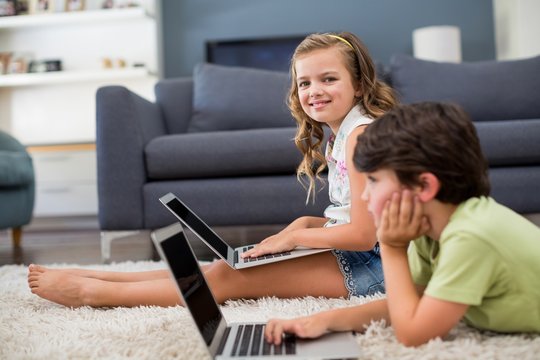 Siblings using laptop in living room
