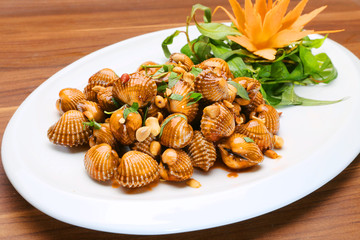 Sauteed blood cockles with peanuts and laksa leaves on white platter