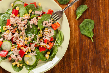 Fresh spinach salad with tuna, cucumber, corn, and red paprika o