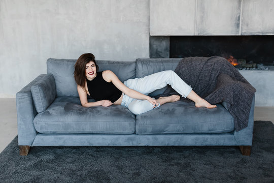 girl lying on the couch. Room in loft style. Room with a fireplace. Happy smiling girl. Girl