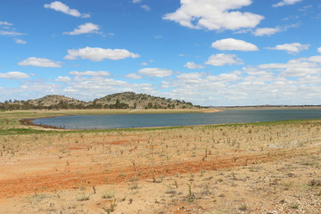 Fototapeta na wymiar Reservoir with receding water levels and bright blue sky