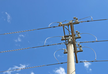 cement power pole and three power electricity lines in cloudy blue sky
