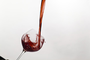 Rotwein wird in ein Weinglas eingegossen