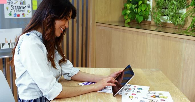 Smiling female executive using digital tablet at desk