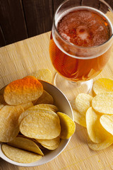 Lager beer in glass and potato chips on wooden background