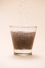 Glass of water with cup of healthy chia seeds and spoon. Text space.