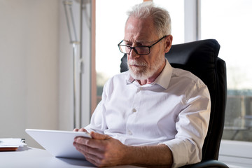 Senior businessman using a digital tablet, hard light