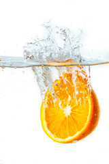 Fototapeta premium orange halves falling into water on white background.