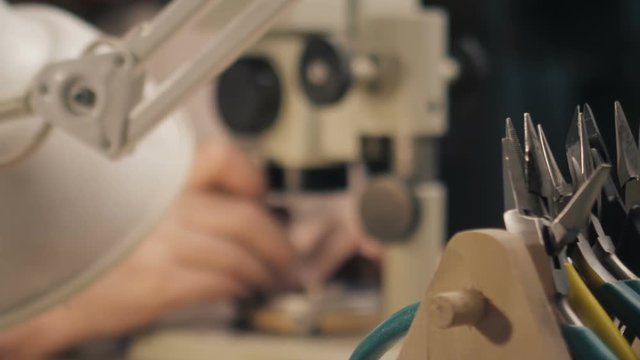 A jeweler is working by the microscope