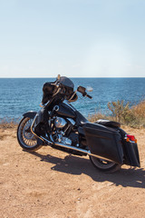 Fototapeta premium Black motorcycle on beautiful seacoast and blue sky. Prairie, steppe, summer.