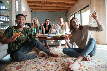 Screaming Happy Five friends sitting in house and eating pizza